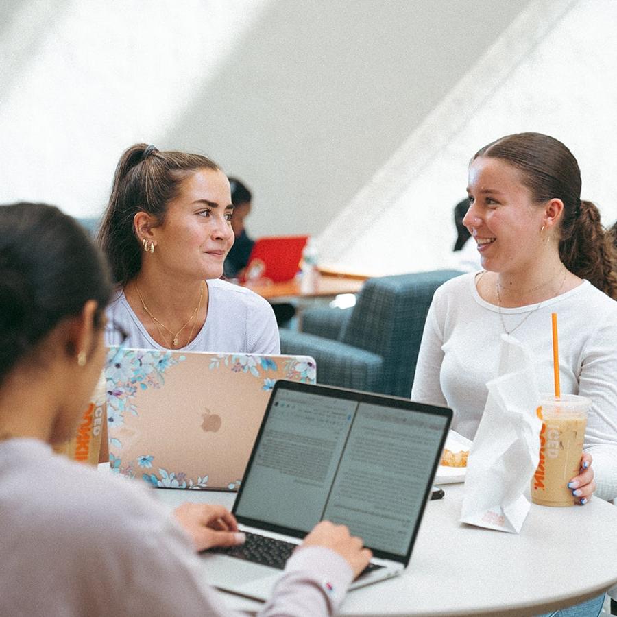 girls studying around table one looking at other who's holding coffee cup