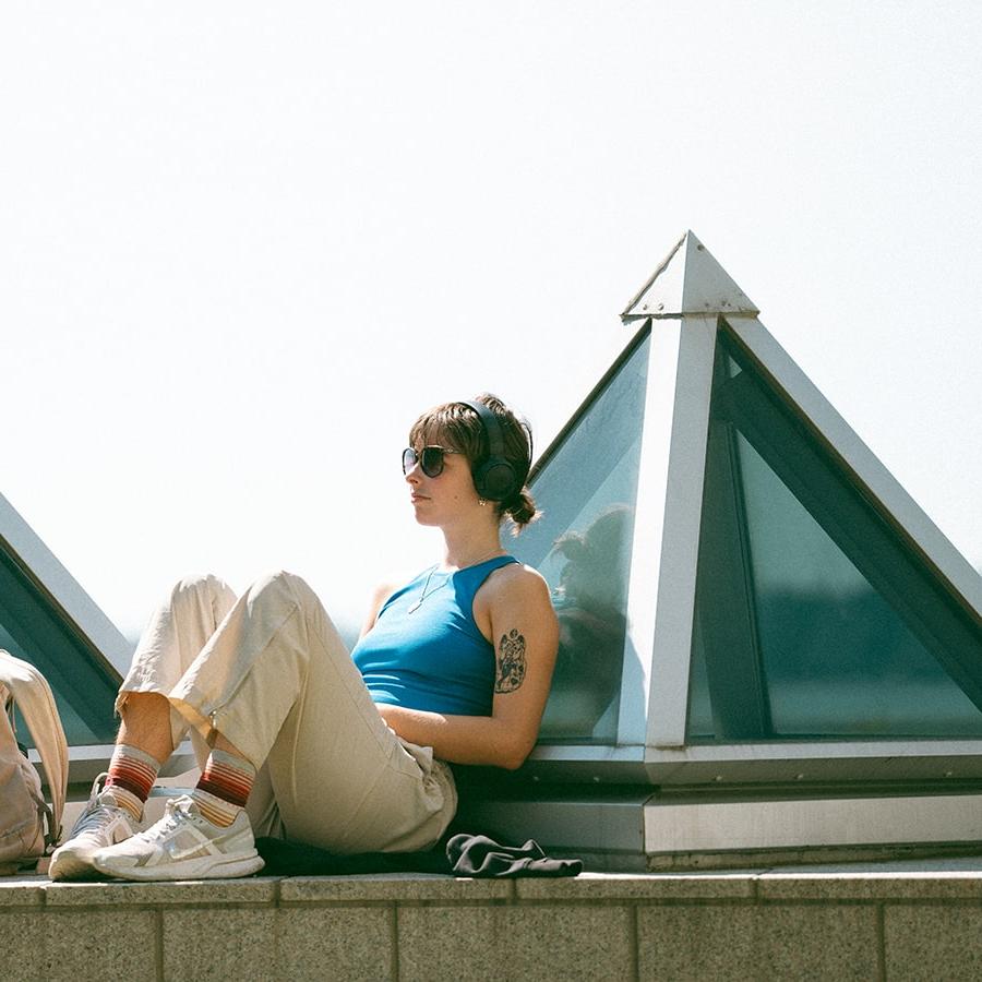 student sits relaxing with headphones on the pyramids outside Campus Center