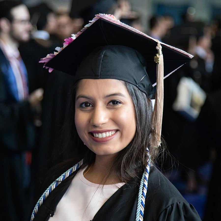 Smiling girl at graduation in cap & gown.